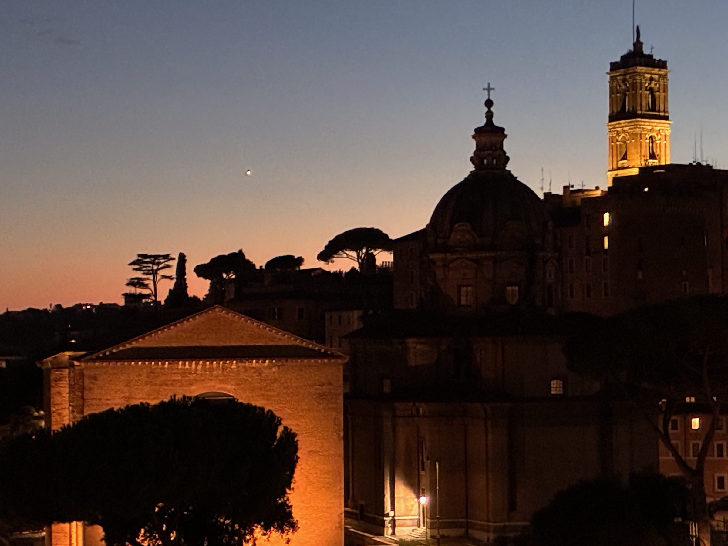 Domes and a bell tower silhouetted against the sky at dusk in Rome