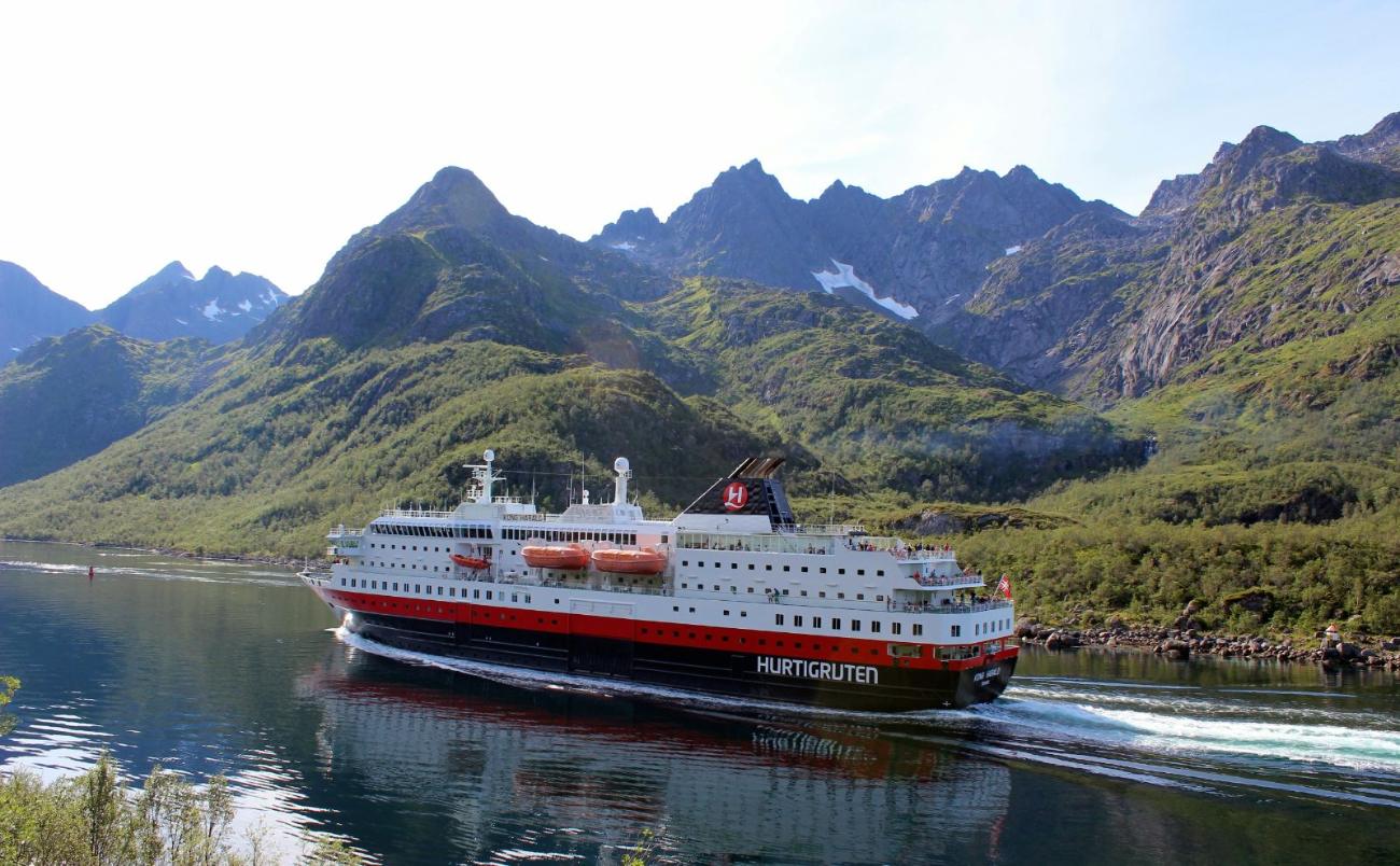 A Hurtigruten coastal ship sailing past Norwegian mountains
