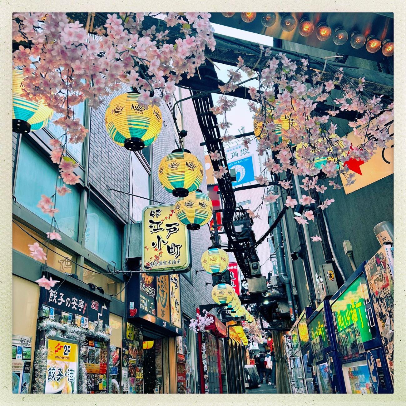 A narrow Tokyo alley of food stalls lit by red lanterns