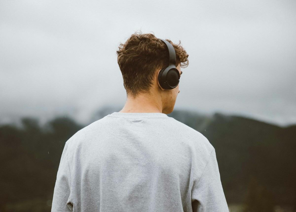 A young traveler wearing headphones looking out over a misty landscape