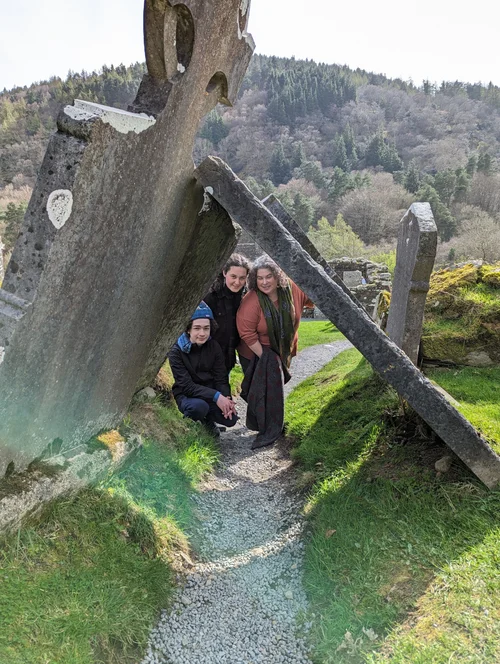 Two travelers on a stone path through green countryside