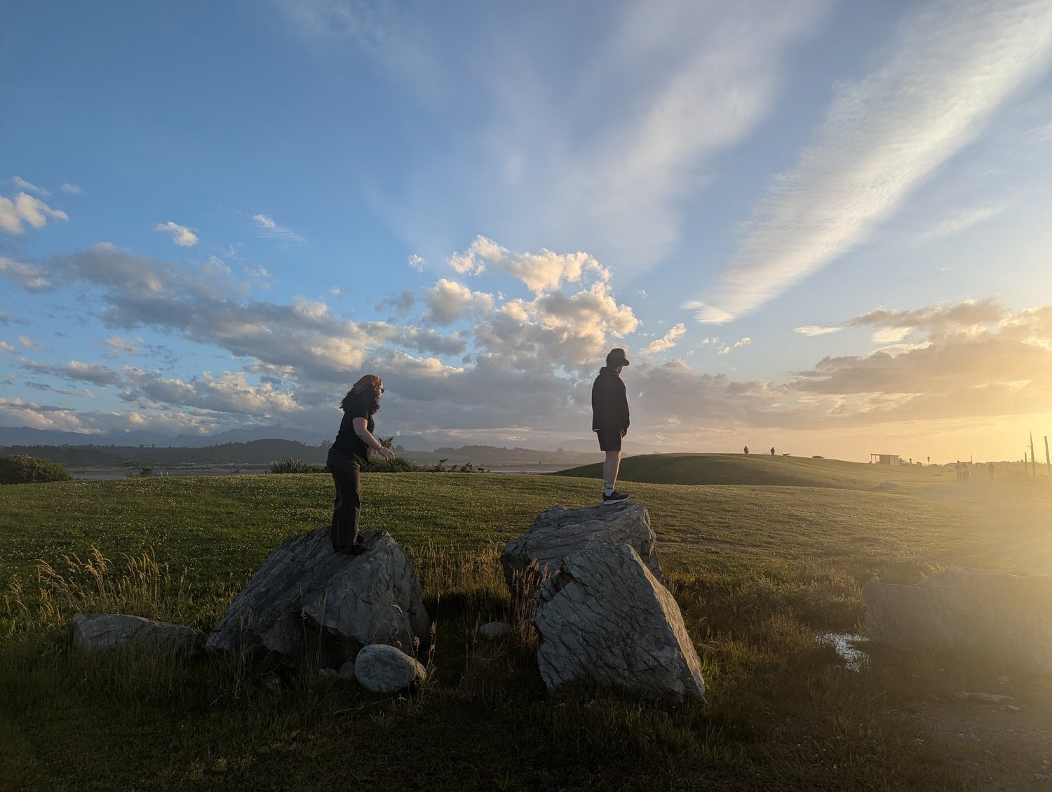 Two figures on coastal rocks at sunset