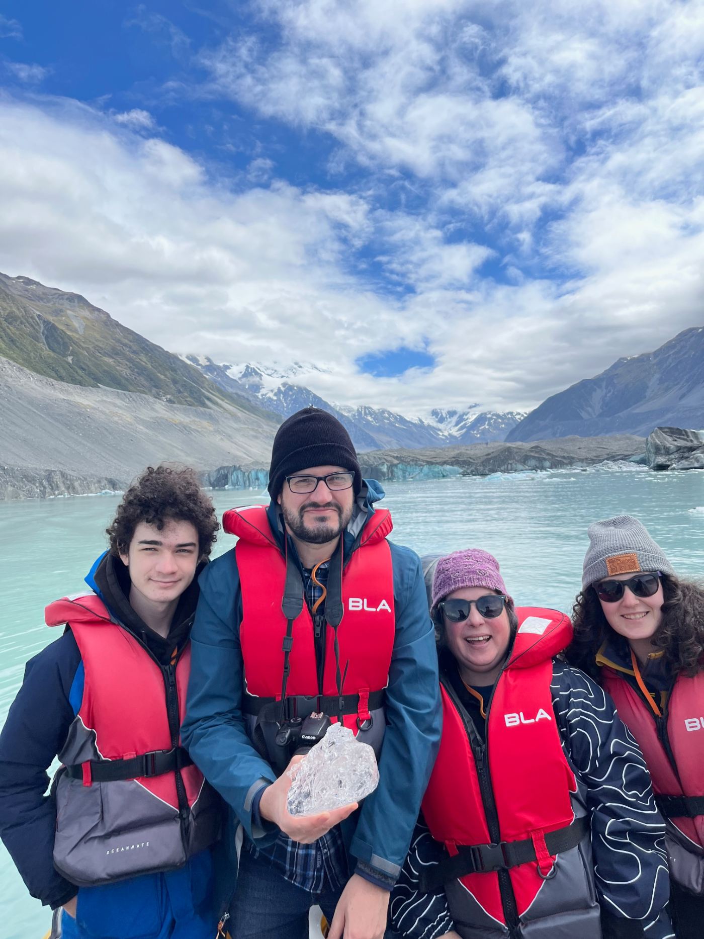 Rebecca and her family in life jackets on a boat in front of a glacier in New Zealand